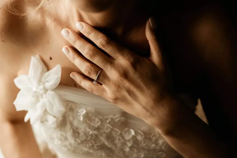 Mão da noiva com o anel junto ao vestido