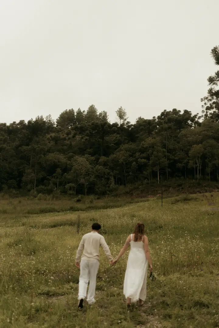 Casal de mãos dadas caminhando pelo campo